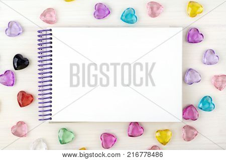 Blank notepad on spirals. Place for text. Around colored decorative hearts. Mok up