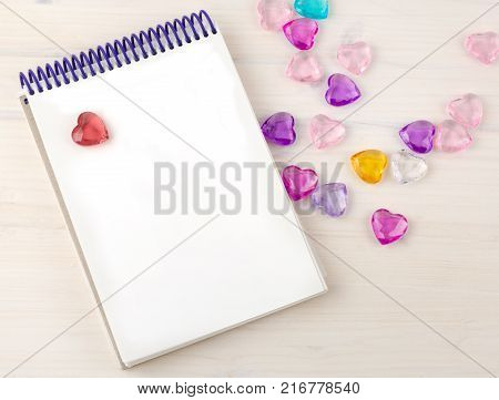 Blank notepad on spirals. Place for text. Around colored decorative hearts. Mok up