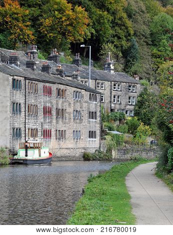 the rochdale canal at hebden bridge with towpath boat and stone houses