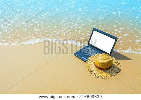laptop or computer notebook on sea beach and wave - business travel background with empty white screen clipping path