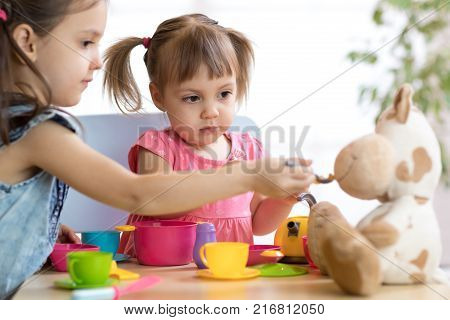Close-up portrait of cute adorable little kids feeding caw soft plush toy