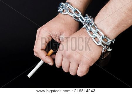 hands tied with a chain with a cigarette. concept of harm to tobacco smoking