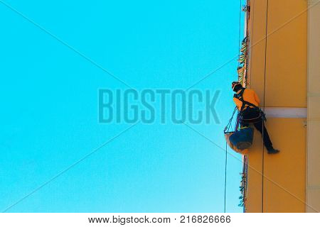Construction and renovation background. Worker climbing on the wall. Man working at height