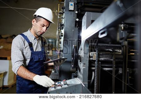 Modern technician with touchpad consulting online recommendations about repairing industrial machines