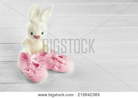 Baby's first bootees and toy on wooden table