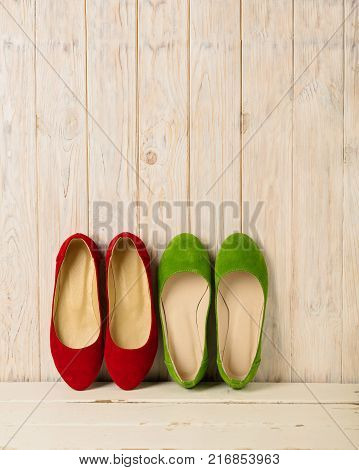 Red and green women's shoes (ballerinas) on wooden background. Selective focus.