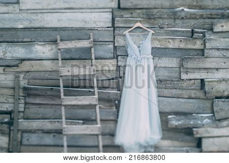 A Beautiful Dress Of Gray Hanging On A Hanger On A Wooden Background