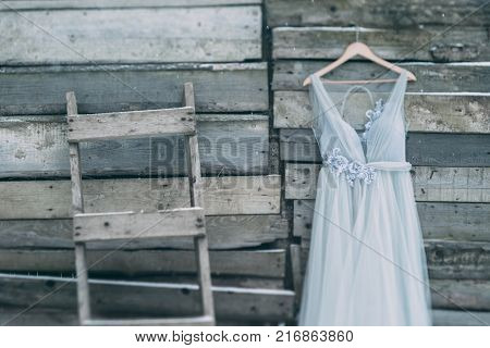 A Beautiful Dress Of Gray Hanging On A Hanger On A Wooden Background