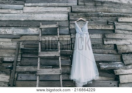 A Beautiful Dress Of Gray Hanging On A Hanger On A Wooden Background