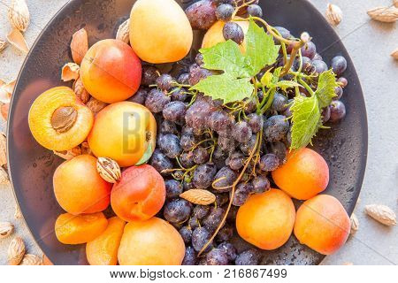 Fruit plate with grapes, apricot and almond on gray. Helthy food backround. Poster, magazine cover