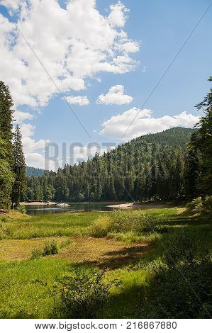 Majestic mountain wild forest lake. Beautiful clouds in the sky