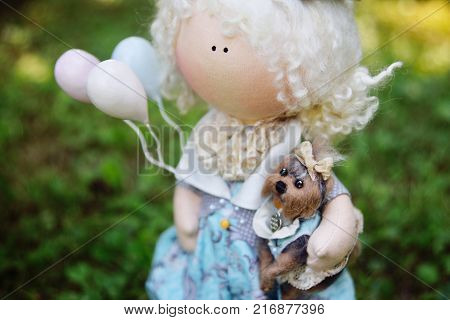 A handmade doll holds balloons and a small dog. Nostalgia, magic, kindness, childhood, dreams