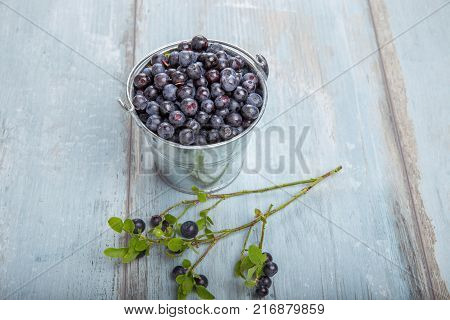 Fresh forest berry, blueberries in a glass plate on a wooden table.
