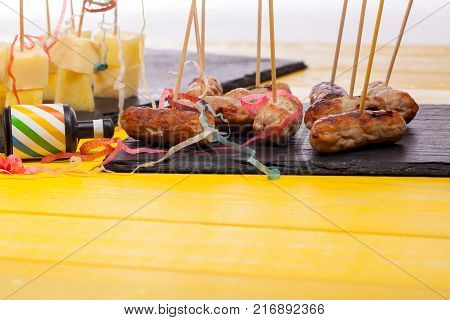 Party food leftovers. Nibbles left over from a Christmas party. Close up of cocktail sausages and cheese and pineapple on sticks with party popper and streamers.