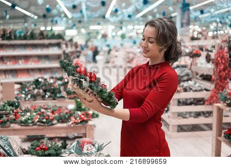 customer woman choosing Christmas decorations. Various choice of New Year's wreath with decorations