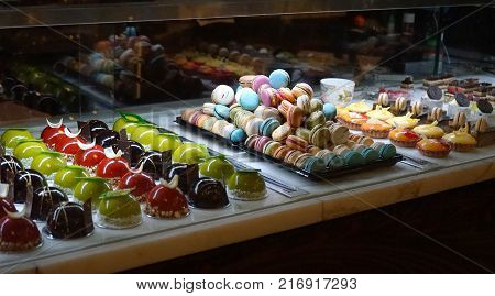 Different types of cake desserts in pastry shop glass display dark background