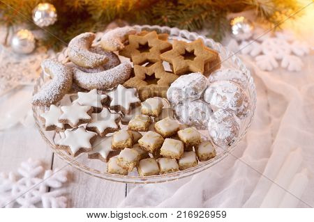 Festive cookies assorted vanilla crescents, cinnamon stars, gingerbreads and cubes and stollen on a festive background. Selective focus.
