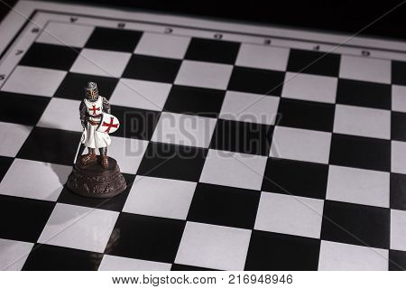 Lonely pewter chess piece, the Bishop on the Board black-and-white cage.