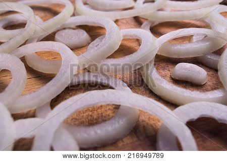 sliced rings onion, lying on a wodden cutting board close-up