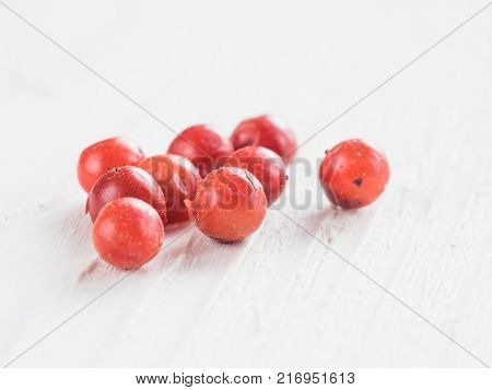 Heap of dried pink pepper berries on white wooden table. Close up view of pink peppercorn. Copy space.