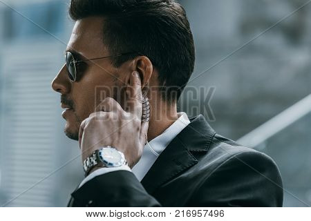 profile of handsome bodyguard with sunglasses and security earpiece