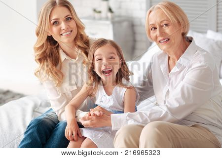 Female guardianship. Delighted positive nice family sitting together and having fun while having a wonderful time at home