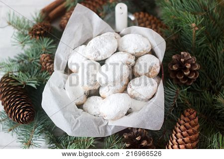 Mini stollen or stollen candy in a tin on a background of fir branches and cones. Selective focus.