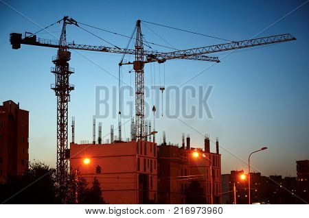 building of a skyscraper by cranes at night.