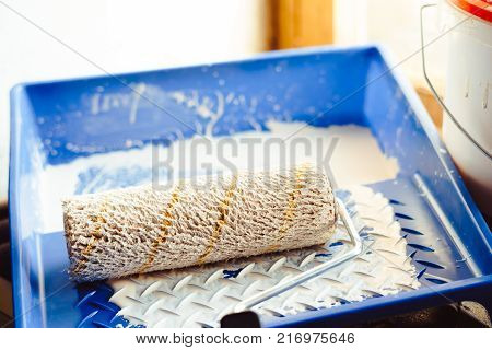 tray with white paint and roller for repair