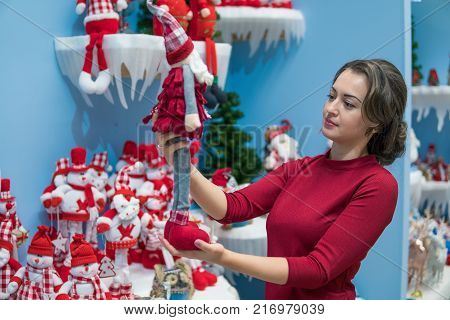 Cheerful happy customer girl choosing gifts for Christmas and New Year. She is holding snowman toys