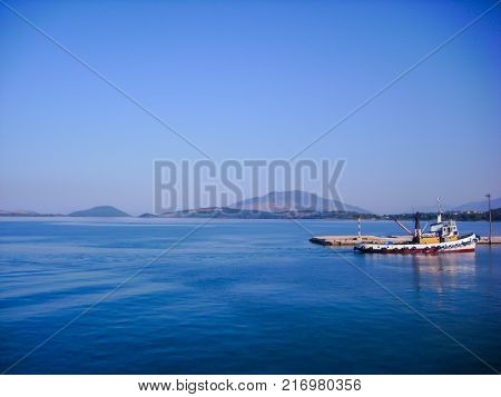 small colorful fishing boat anchored at dock in calm water with blue sky