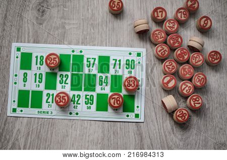 Developing bingo table game old lotto game with wooden elements and cards bingo on a wooden background.