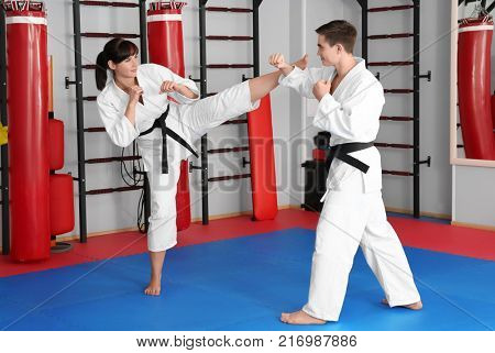 Young man and woman practicing karate in dojo