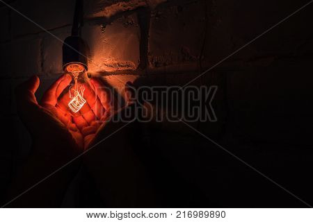 a warm lamp in their hands, light in the palms, a brick wall