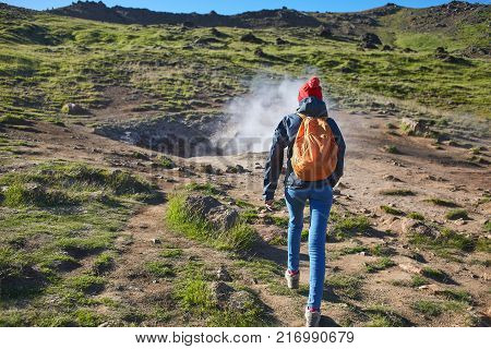 back view of woman traveler on a walk in the Valley of the river of Hveragerdi Iceland. Hiking Tour of Reykjadalur Hot Springs