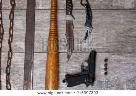 A bandit chain gun, a machete, a bat, knives and a bullet with bullets lie vertically on the wooden floor