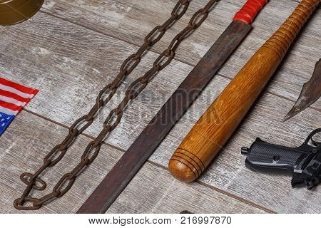 A bandit weapon is a homemade machete, a rusty chain and a bit lies on a wooden background. Top view from an angle