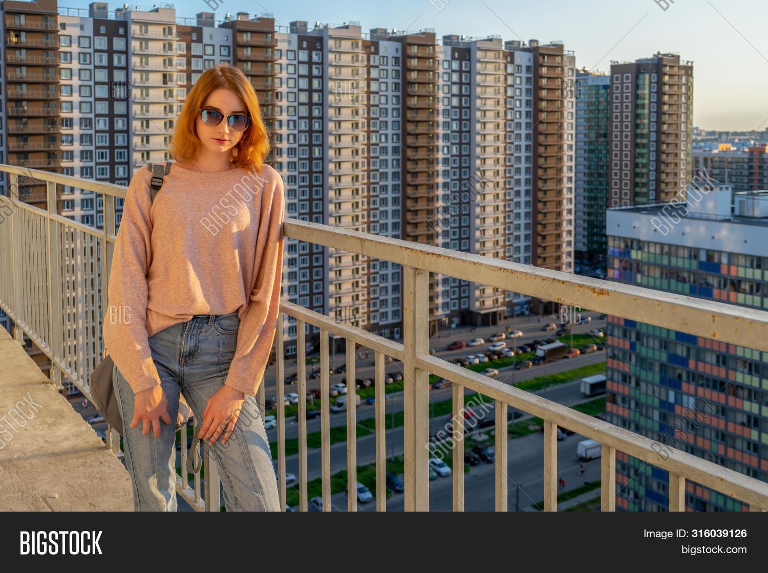 Девушка в джинсах гуляет на балконе 