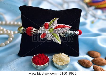 Beautiful Rakhi With Roli Chawal And Almonds On Silk Background