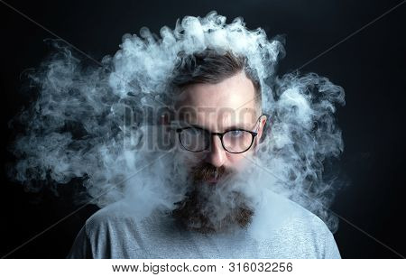 Concept. Smoke Enveloped The Head Man. Portrait Of A Bearded, Stylish Man With Smoke. Secondhand Smo