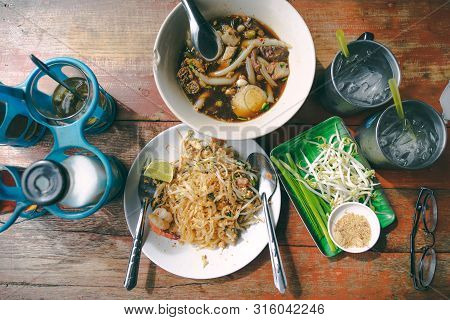 Top View Thai Street Food On Old Wooden Table Padthai And Guay Jub Noodle, Popular Traditional Thai 