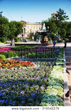 Russia, Irkutsk - July 7, 2019: Flower Bed, Fountain And Historical Building In Tikhvinsky Or Kirov 