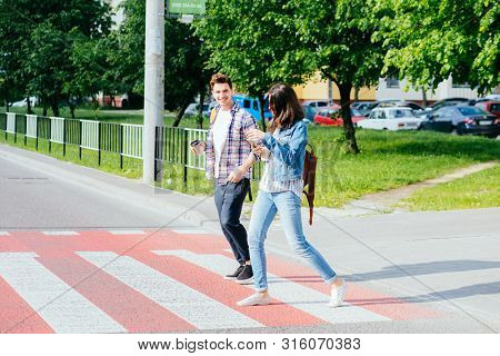 Happy Couple Students Boy And Girl In Casual Clothes Crossing A Wide Street On A Pedestrian Crossing