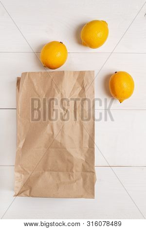 Paper Bag On Wooden White Background With Empty Space For Text. Flat Lay, Top View.