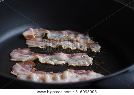 Bacon Slices Being Fried In Frying Pan.