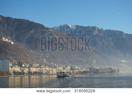 Montreux, Switzerland - 02 17, 2019: Ship Cruising Towards Montreux With Mountains In The Background