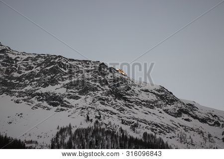 Last Rays Of Sun Illuminate The Mountains Covered With Snow At Evening