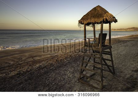 A Lifegaurd Tower Hut On A Beach At Sunrise/sunset.