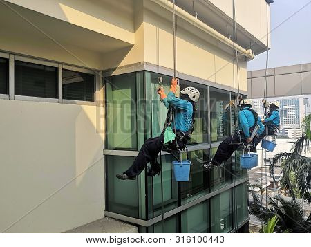Rope Access Cleaning Worker Wearing Safety Harness Hard Hat Working At Height Descending On Rope Per