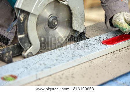 A Construction Contractor Worker Using A Worm-driven Hand-held Circular Saw To Cut Boards And Plasti